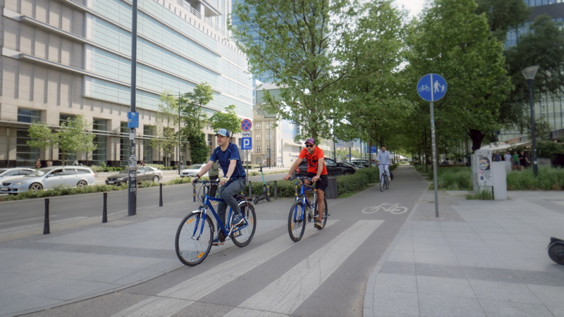 3 - Street scene featuring individuals cycling along a dedicated urban bike path